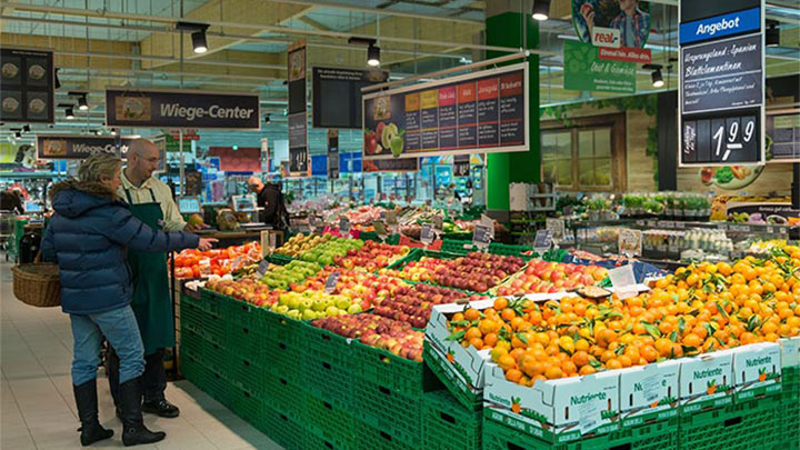 Müşteriler Philips süpermarket aydınlatması kullanılarak aydınlatılan Real'deki meyvelere bakıyor