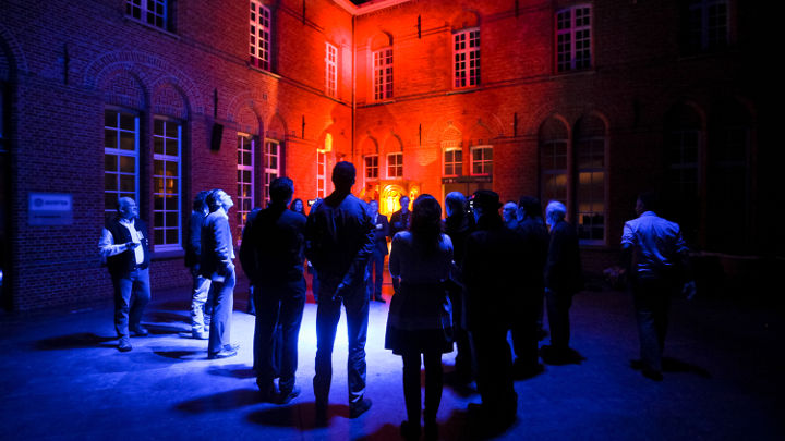 Büyük bir grup insan Philips tarafından düzenlenen bir atölyede Turnhout, Belçika'daki güzelce aydınlatılmış bir binanın dışında tartışıyor