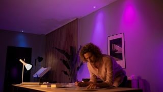 Philips Hue akıllı LED ışıkları, oturma odasında canlı mor ve pembe bir atmosfer oluşturarak modern evlerde film geceleri ve rahatlama için özelleştirilebilir ortam aydınlatmasını sergiliyor.
