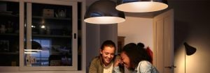 "Modern LED askı lambalar, enerji tasarruflu ev aydınlatma çözümlerini sergileyerek, sohbet eden iki kadın için sıcak bir atmosfer yaratıyor."